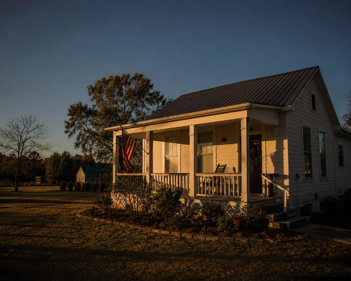 A Warrior Cottages veterans home at golden hour with an American flag