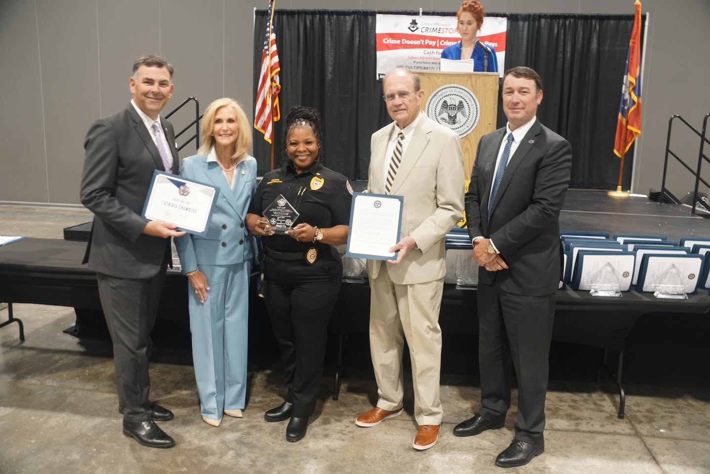 Uniformed officer holding an award with ceremony guests in 2026